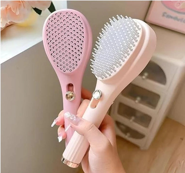 Pink self-cleaning hair brush with retractable dot pad and white bristle side, one-click release